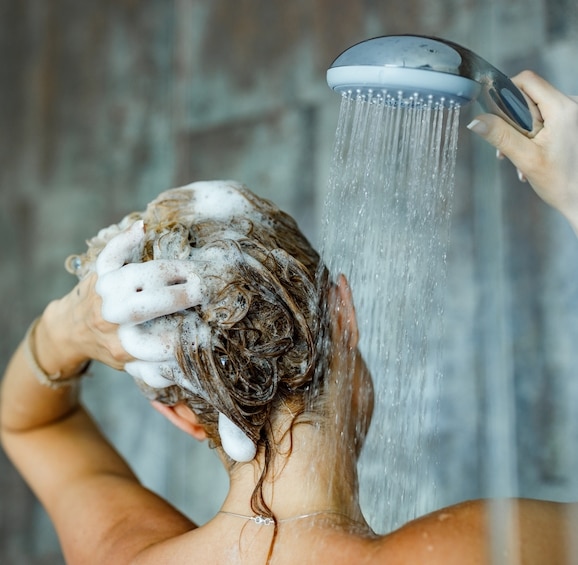 person showering with shampoo in hair